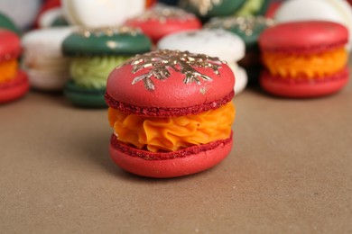 Beautifully decorated Christmas macarons on brown background, closeup