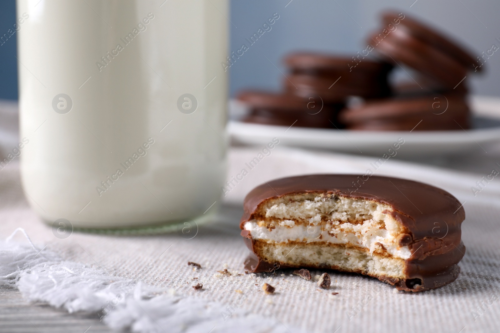 Photo of Tasty choco pie and milk on white napkin, closeup view