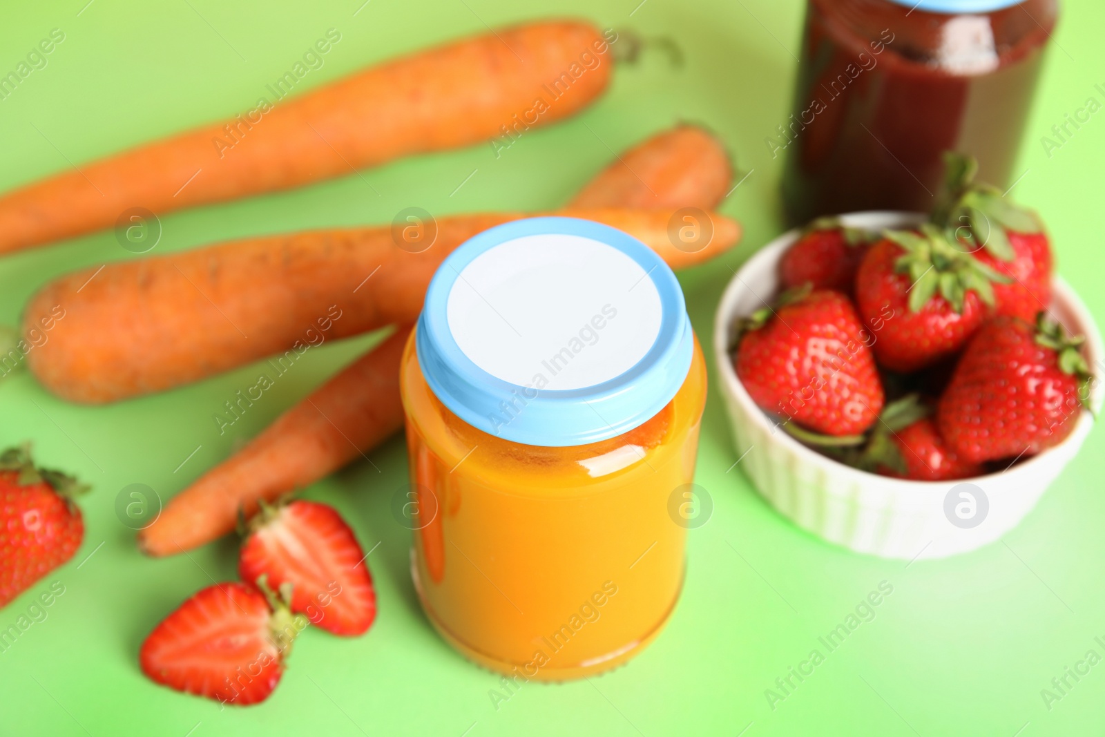 Photo of Jars with baby food and fresh ingredients on green background