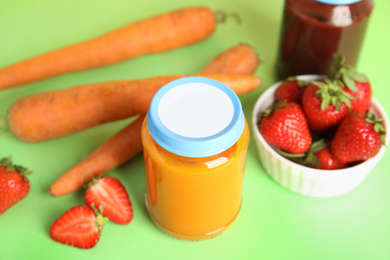 Jars with baby food and fresh ingredients on green background