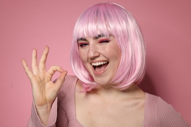 Happy woman with bright makeup and fake freckles on pink background