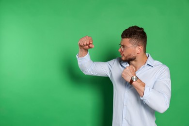 Photo of Young man ready to fight on green background, space for text