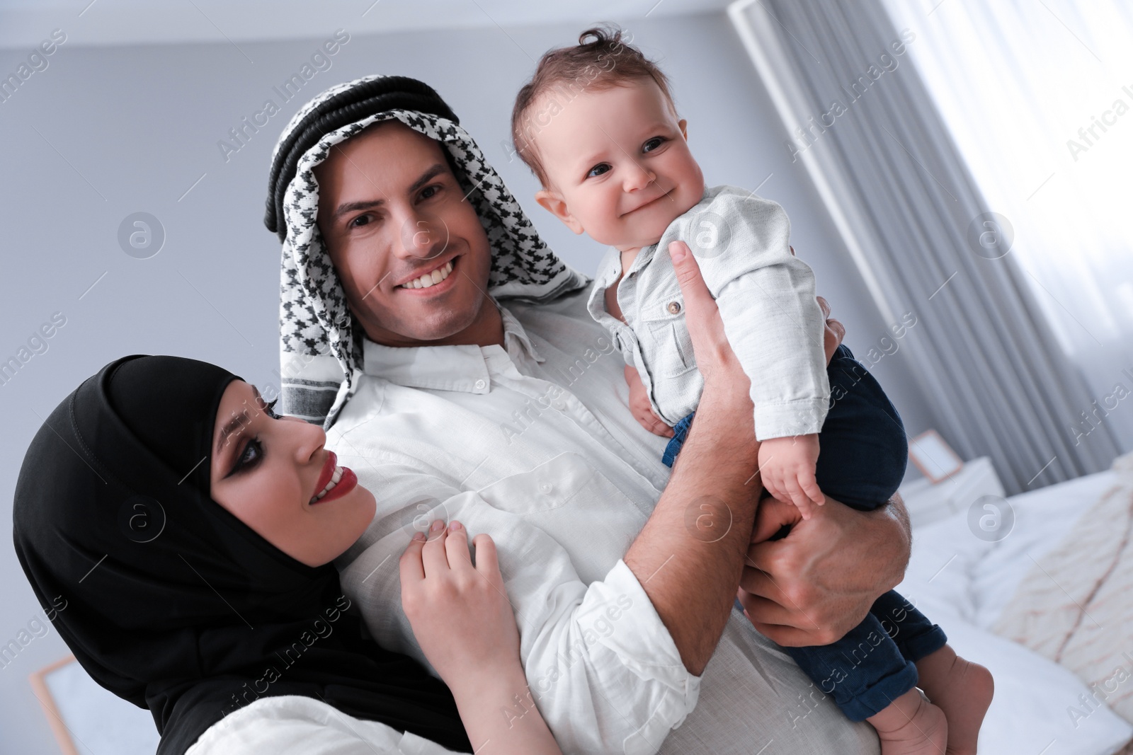 Photo of Happy Muslim family with little son in bedroom