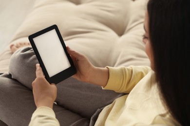 Photo of Young woman using e-book reader on sofa, closeup