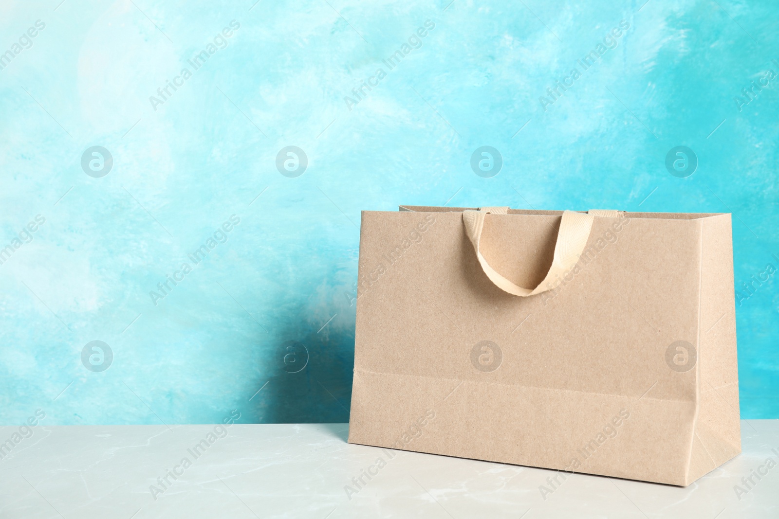 Photo of Paper shopping bag on table against color background. Mock up for design