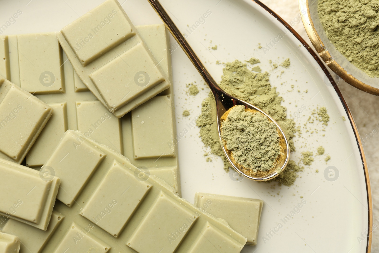 Photo of Pieces of tasty matcha chocolate bar and powder in spoon on table, top view