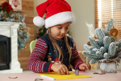 Photo of Cute child writing letter to Santa Claus at table indoors. Christmas tradition