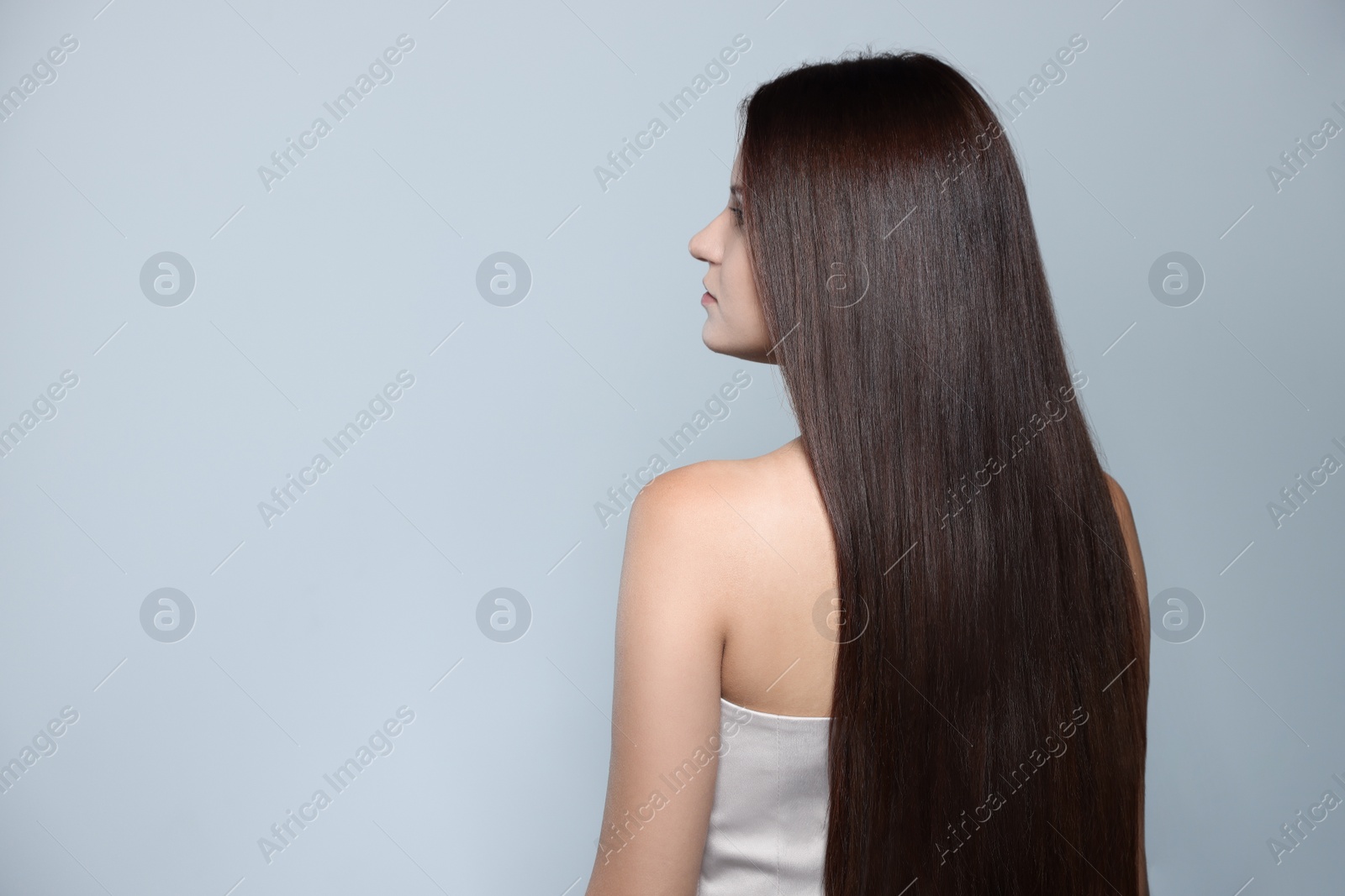 Photo of Beautiful young woman with healthy strong hair on light gray background, space for text