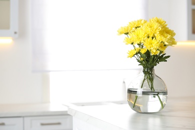 Photo of Vase with beautiful yellow chrysanthemum flowers on table in kitchen, space for text. Stylish element of interior design