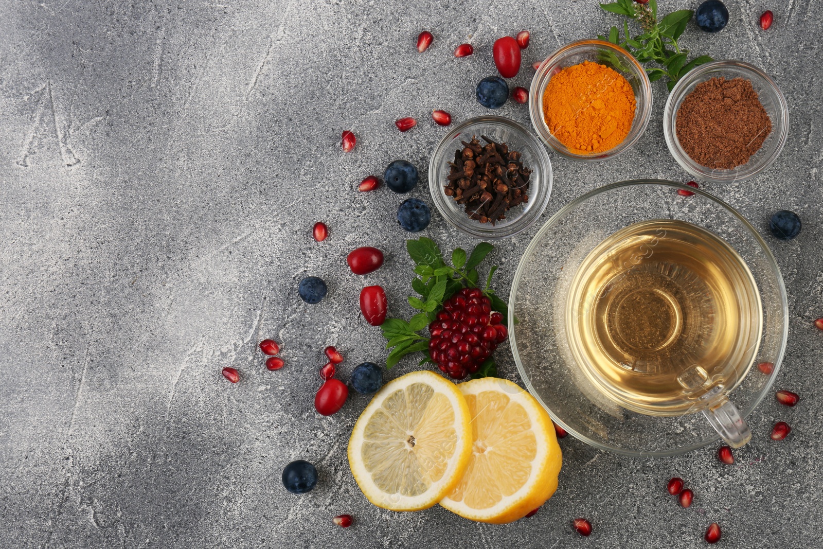 Photo of Cup with delicious immunity boosting tea and ingredients on grey table, flat lay. Space for text