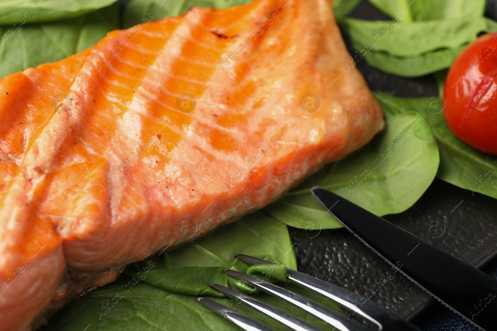 Photo of Tasty grilled salmon with spinach served on table, closeup