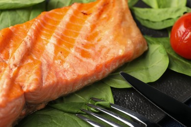 Tasty grilled salmon with spinach served on table, closeup