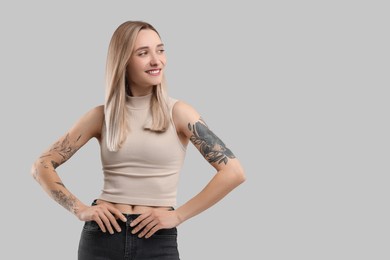 Photo of Portrait of beautiful tattooed woman on gray background, space for text
