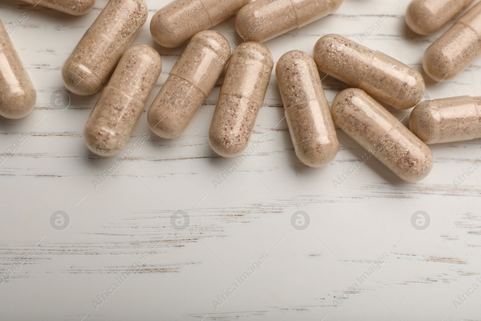 Photo of Gelatin capsules on white wooden table, flat lay. Space for text