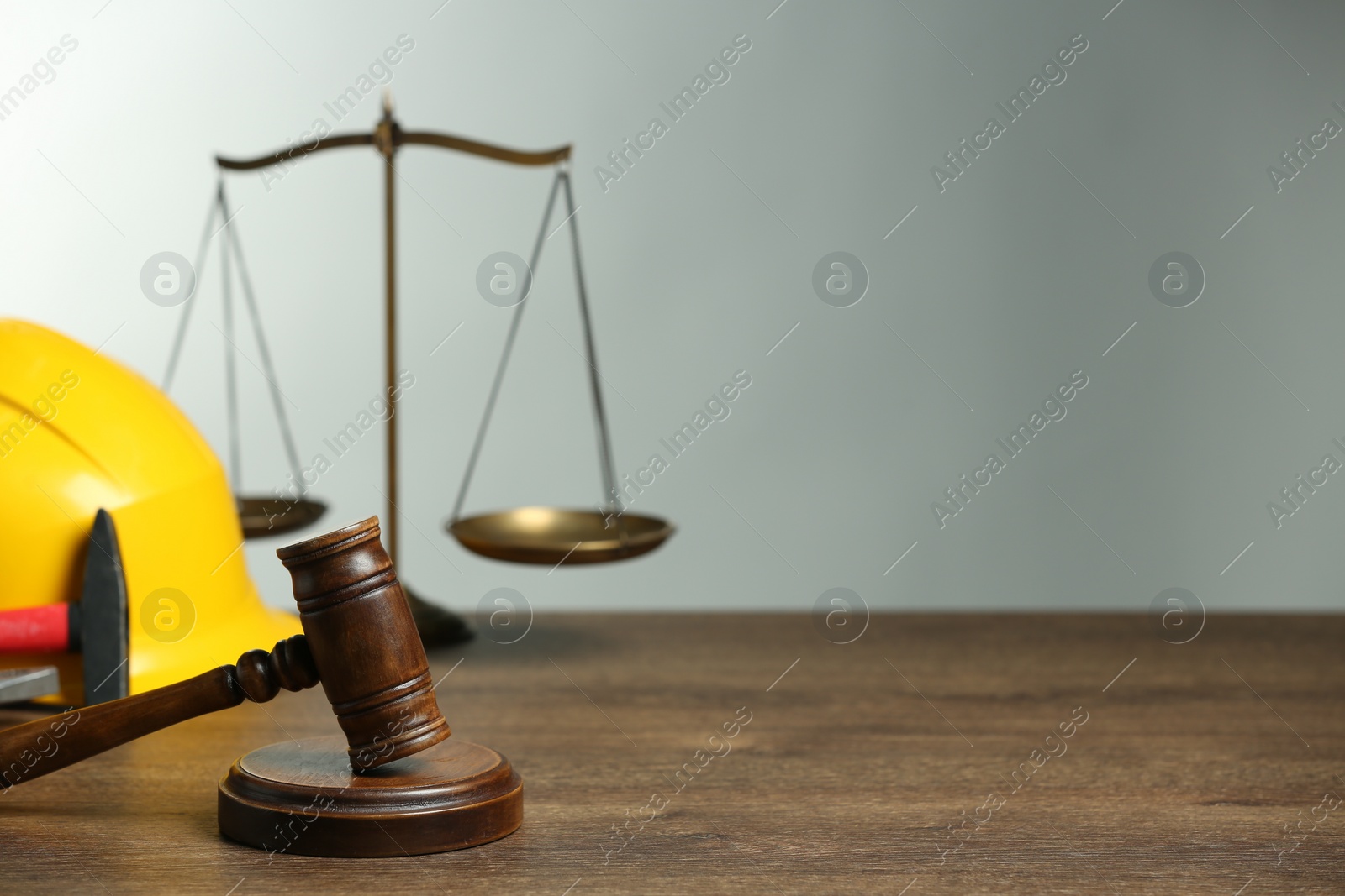 Photo of Construction and land law concepts. Gavel, scales of justice, hard hat and hammer on wooden table, space for text