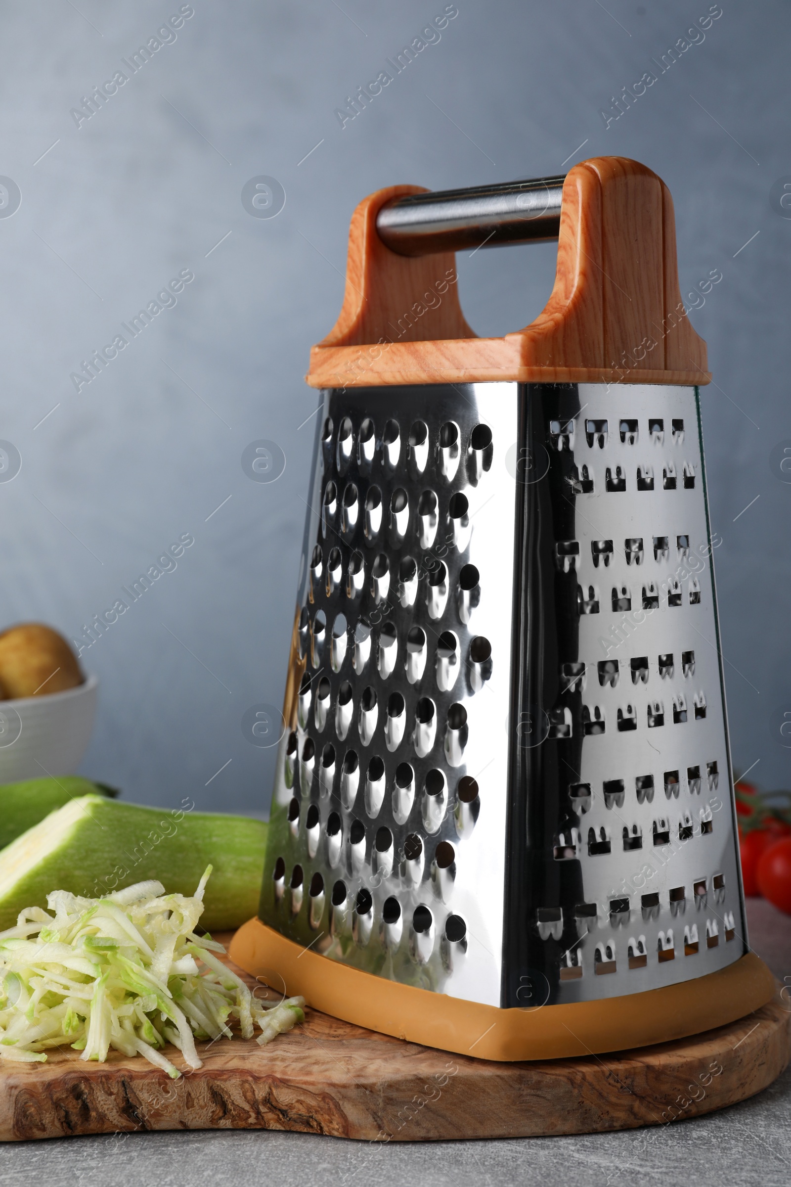 Photo of Grater and fresh zucchini on grey table