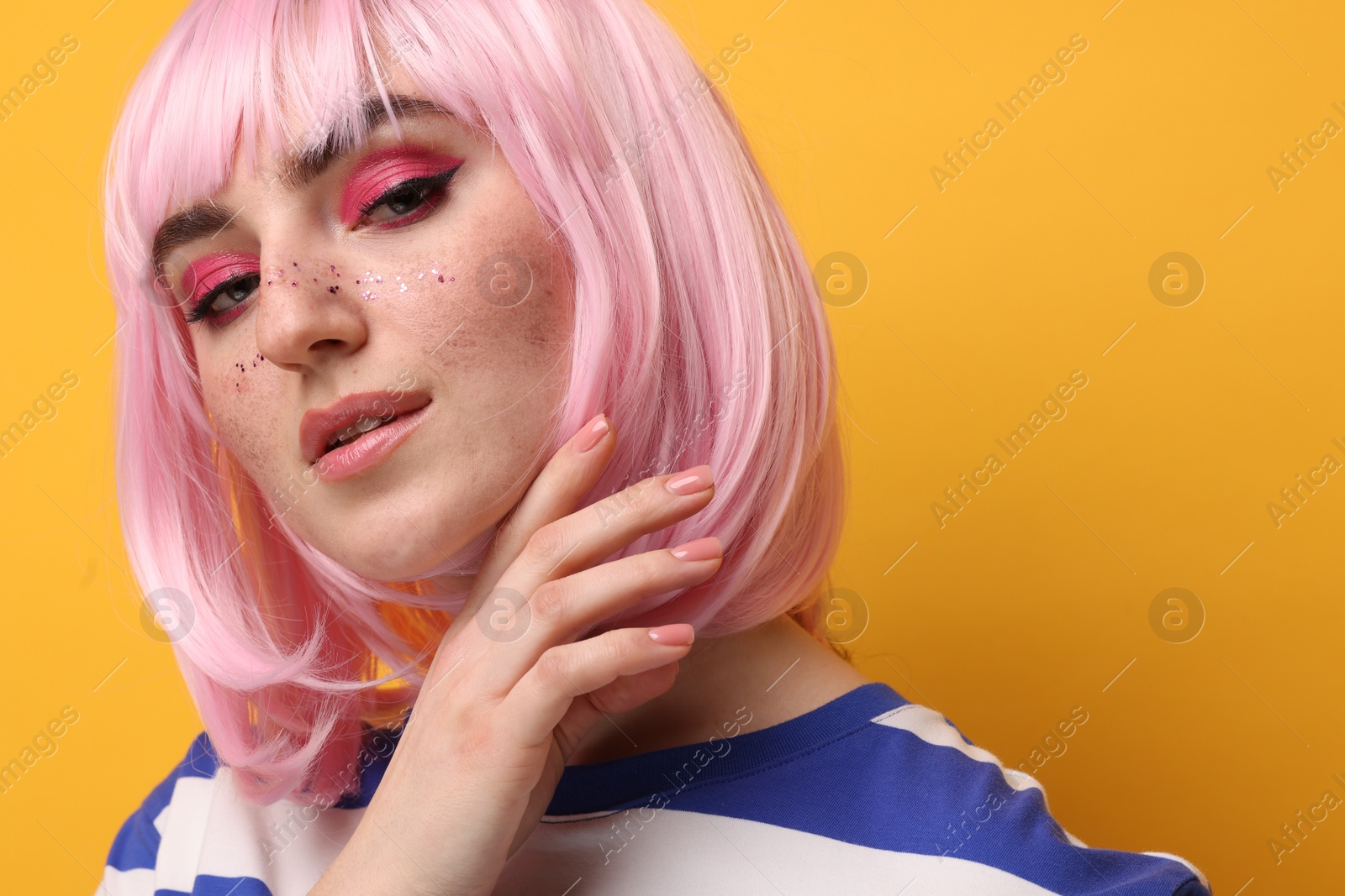 Photo of Beautiful woman with bright makeup and glitter freckles on yellow background, closeup
