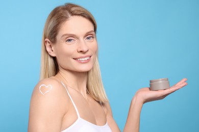 Photo of Woman with jar of body cream on light blue background