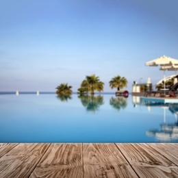 Image of Empty wooden surface near outdoor swimming pool with clear water. Space for design