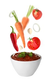 Image of Different ingredients falling into ceramic bowl with delicious adjika sauce on white background