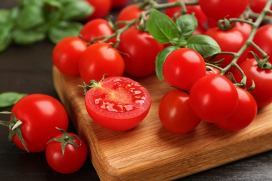 Photo of Fresh cherry tomatoes and basil on wooden table, closeup