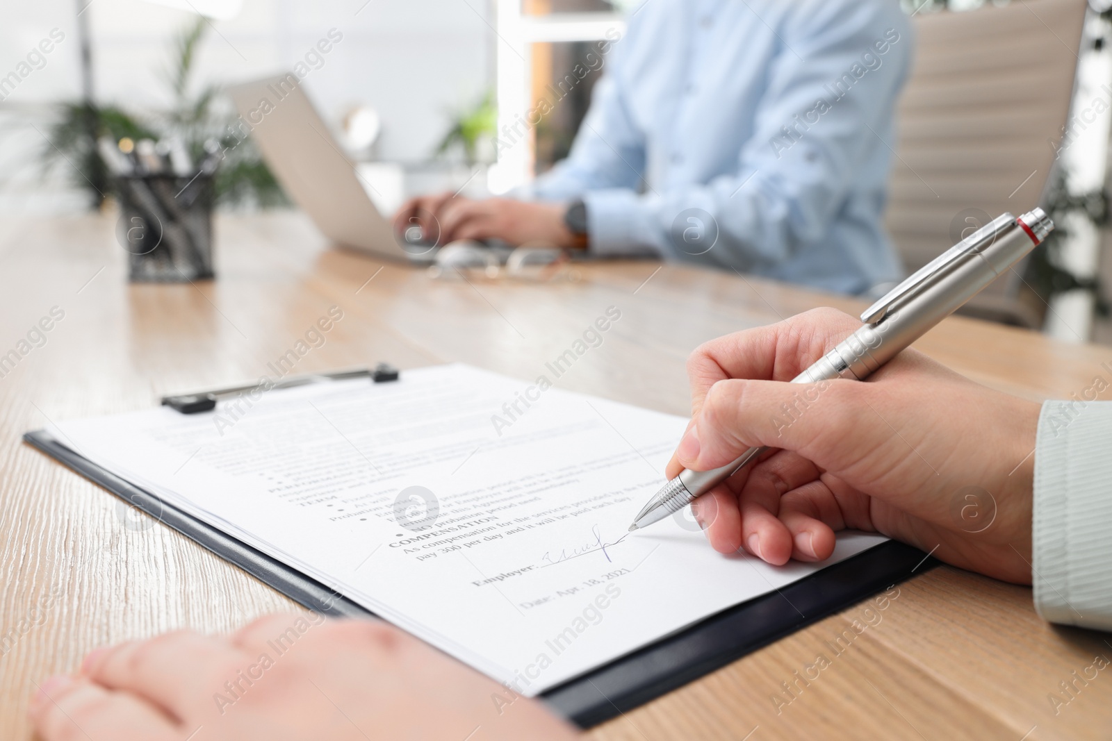 Photo of Woman signing contract at table in office, closeup.