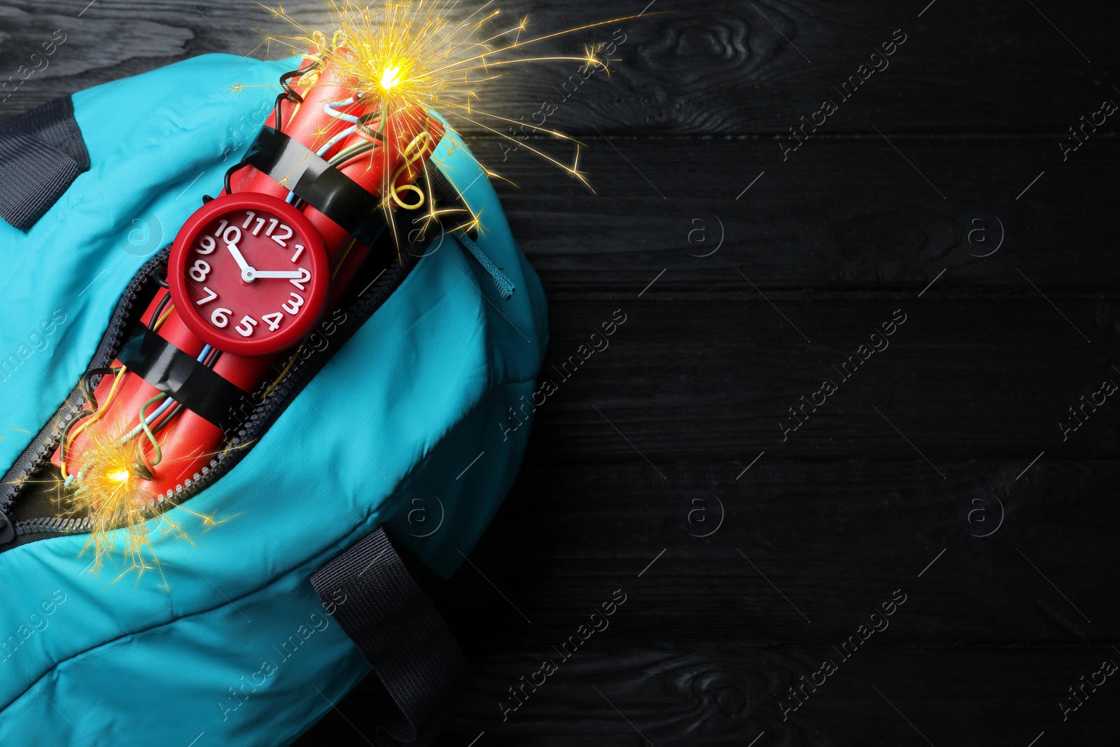 Image of Dynamite time bomb with burning wires in bag on black wooden table, top view. Space for text