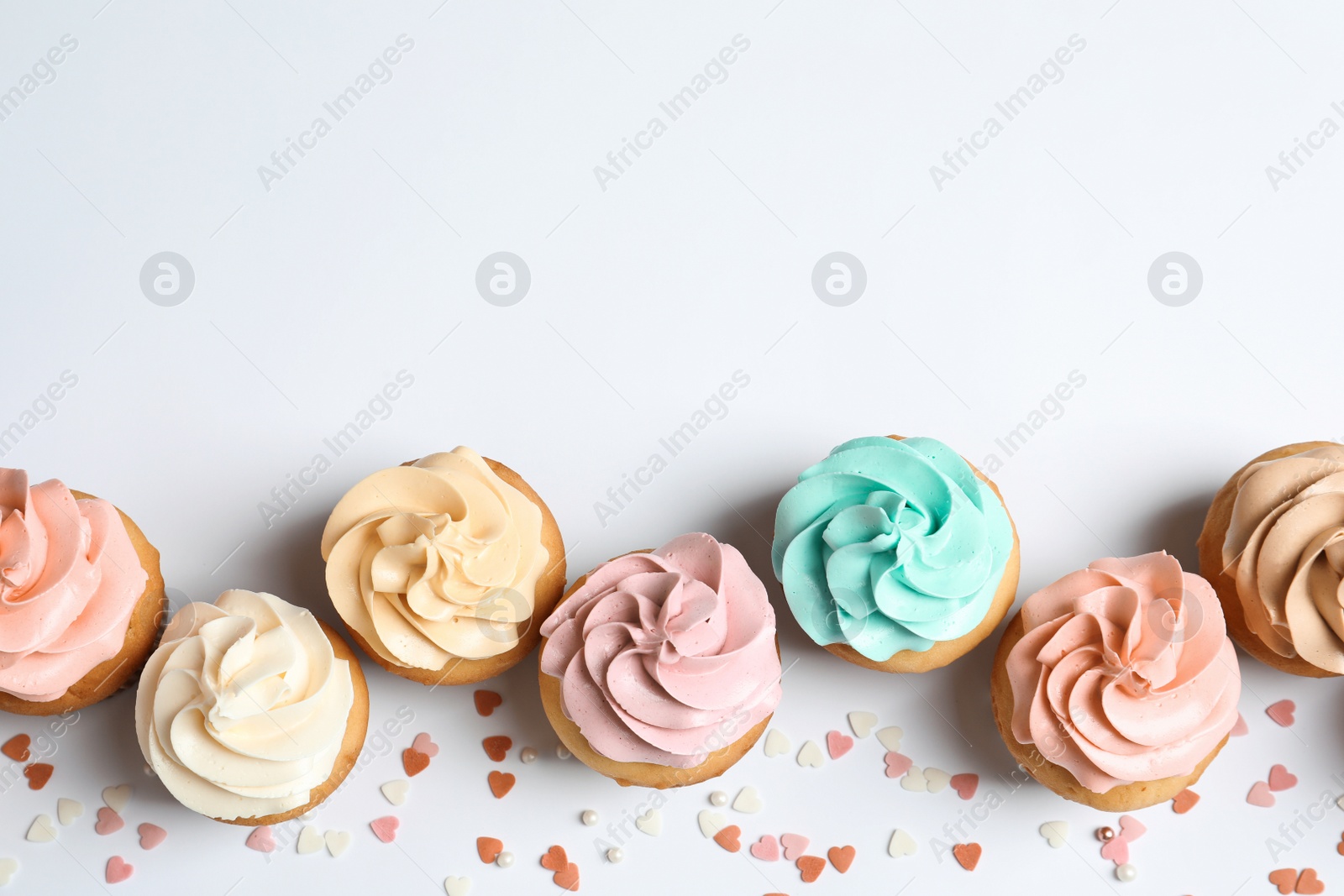 Photo of Flat lay composition with delicious birthday cupcakes and space for text on white background