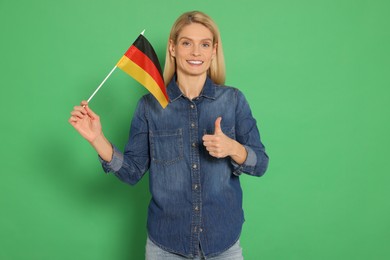 Photo of Woman with flag of Germany showing thumb up on green background