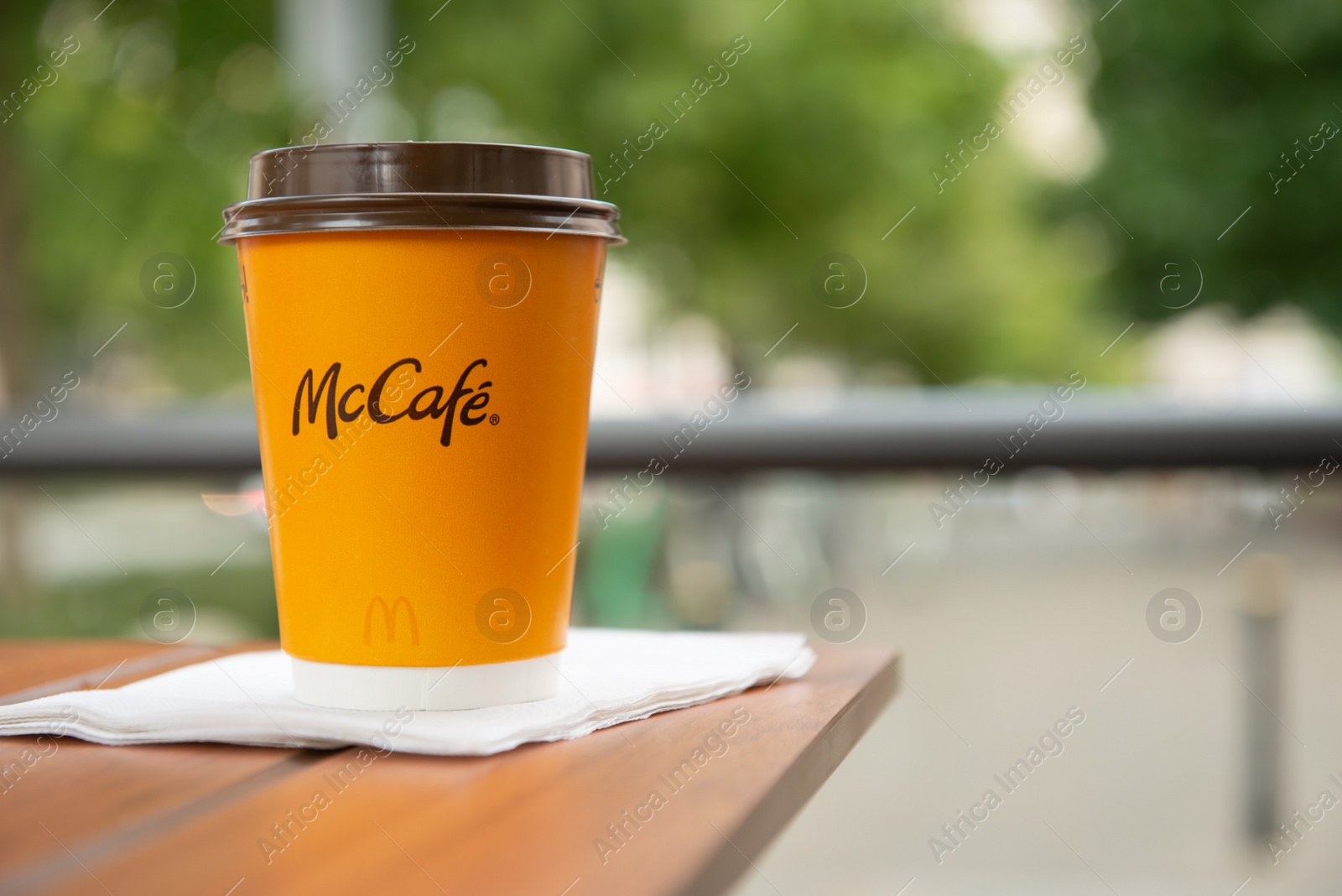 Photo of WARSAW, POLAND - SEPTEMBER 04, 2022: McDonald's hot drink on wooden table outdoors, space for text