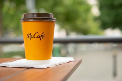 WARSAW, POLAND - SEPTEMBER 04, 2022: McDonald's hot drink on wooden table outdoors, space for text