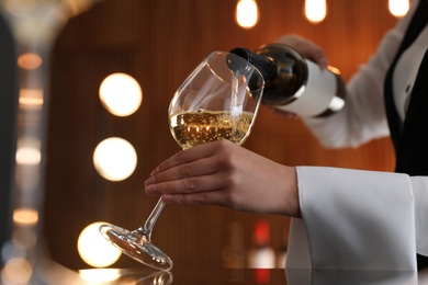 Waitress pouring wine into glass in restaurant, closeup