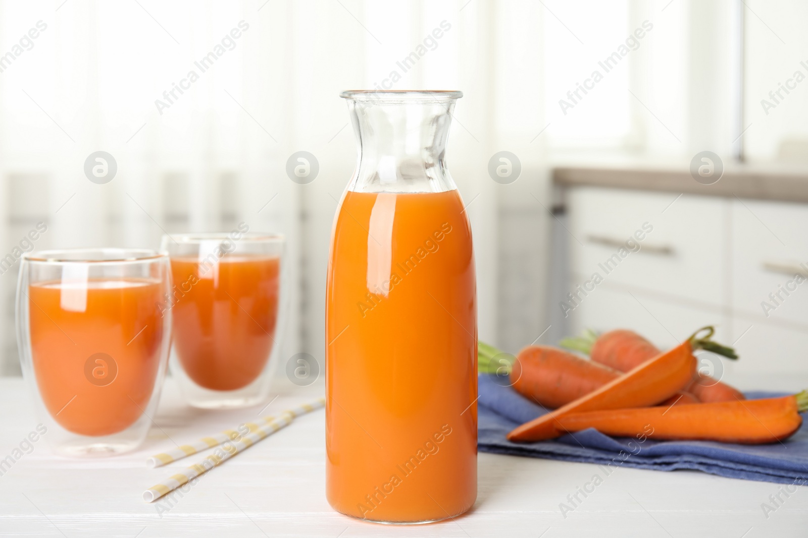 Photo of Freshly made carrot juice on white table