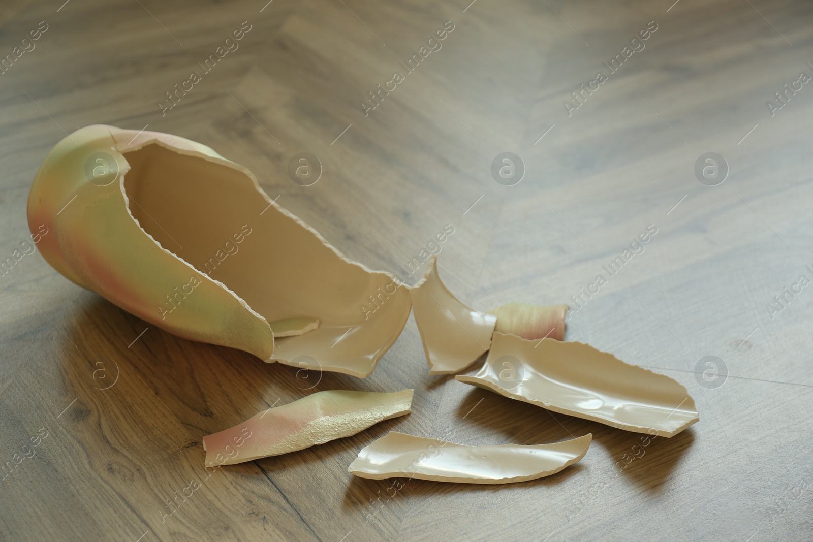 Photo of Broken bright ceramic vase on wooden floor