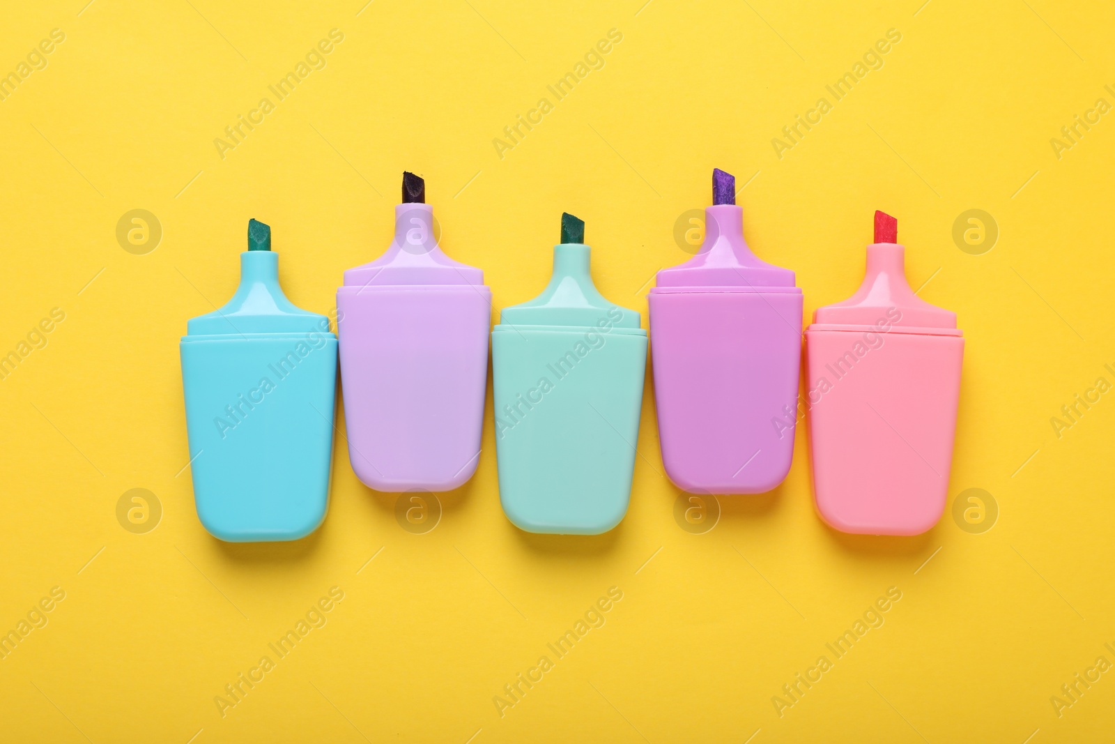 Photo of Many colorful markers on yellow background, flat lay