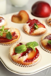 Photo of Delicious cupcakes with plums in baking pan, closeup