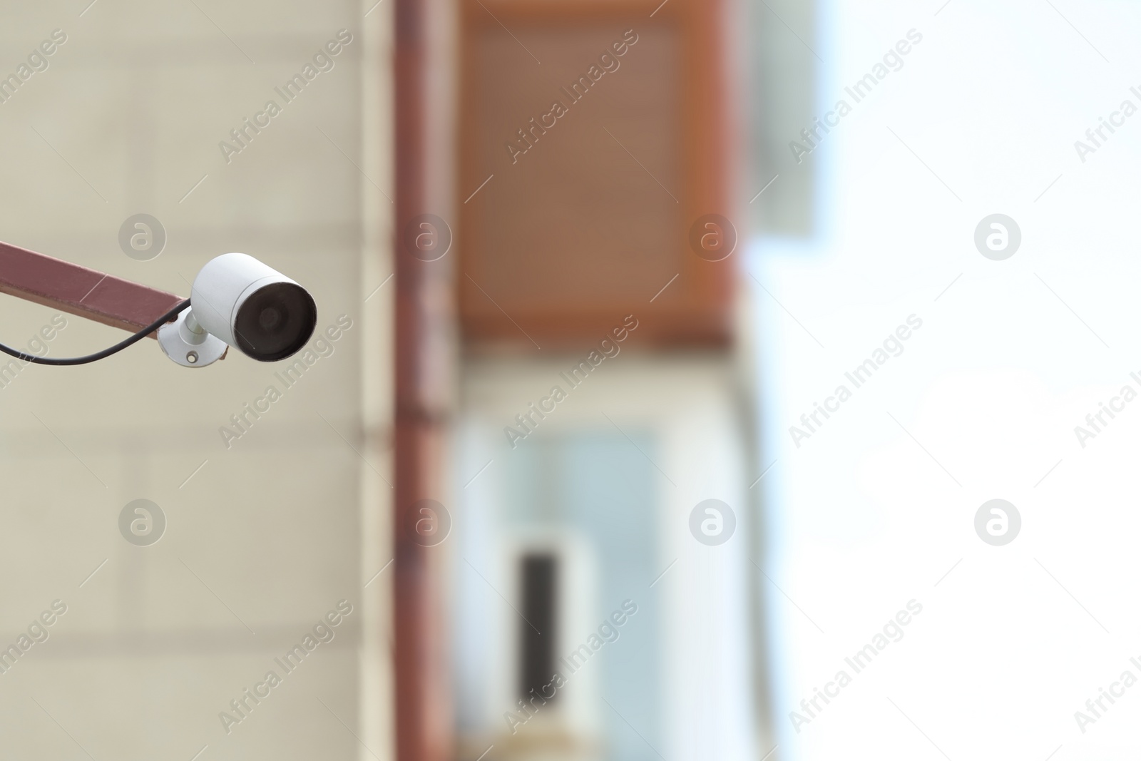 Photo of Modern CCTV security camera on building wall outdoors. Space for text