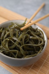 Tasty seaweed salad in bowl served on gray table, closeup