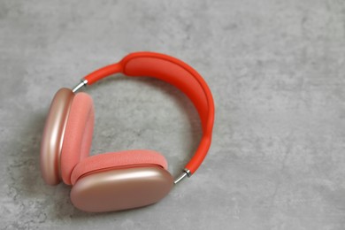 Stylish pink headphones on light grey table, closeup. Space for text