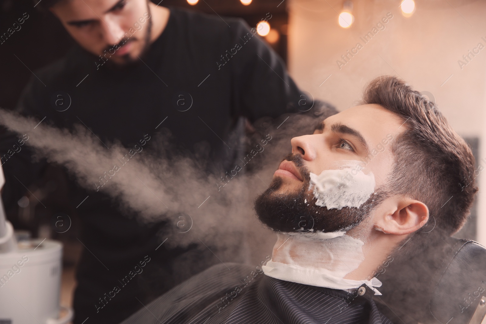 Photo of Hairdresser working with client at barbershop. Professional shaving service