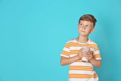 Photo of Adorable little boy with glass of milk on color background