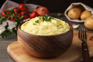Photo of Bowl of freshly cooked mashed potatoes with parsley served on wooden table, closeup
