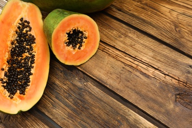 Fresh juicy cut papayas on wooden table, space for text