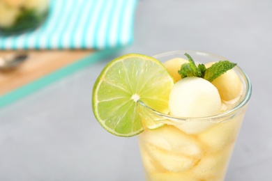 Glass with tasty melon ball drink on table, closeup