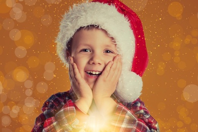 Image of Cute child in Santa hat on yellow background. Christmas celebration