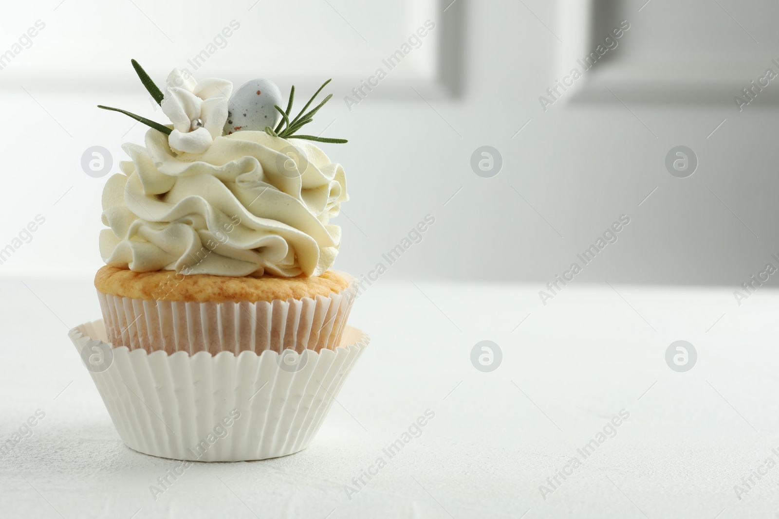 Photo of Tasty Easter cupcake with vanilla cream on white table, space for text