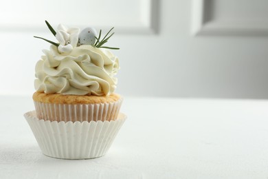 Photo of Tasty Easter cupcake with vanilla cream on white table, space for text