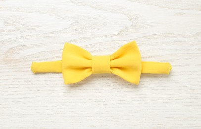 Photo of Stylish yellow bow tie on white wooden background, top view