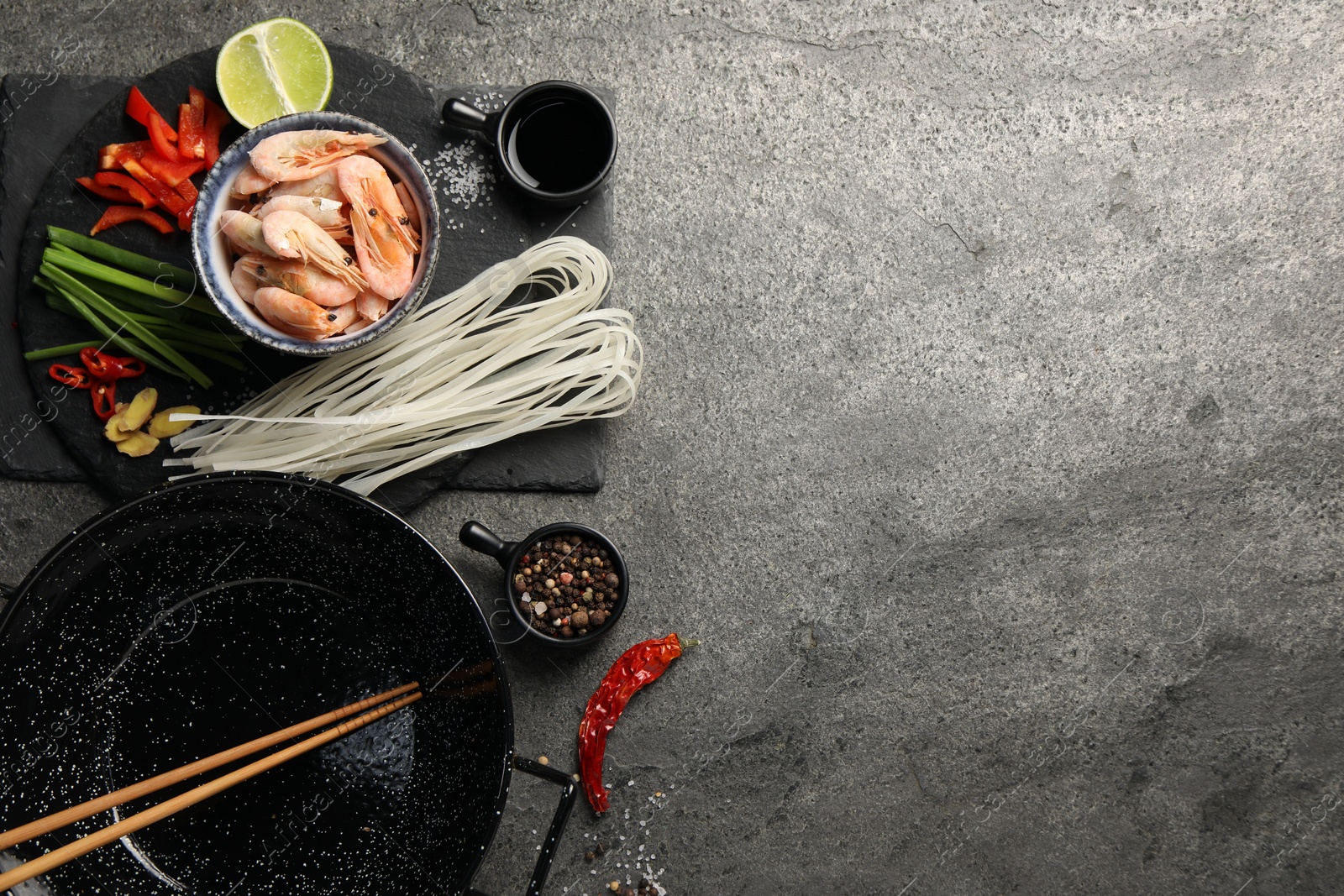 Photo of Flat lay composition with black wok, spices and products on dark textured table. Space for text