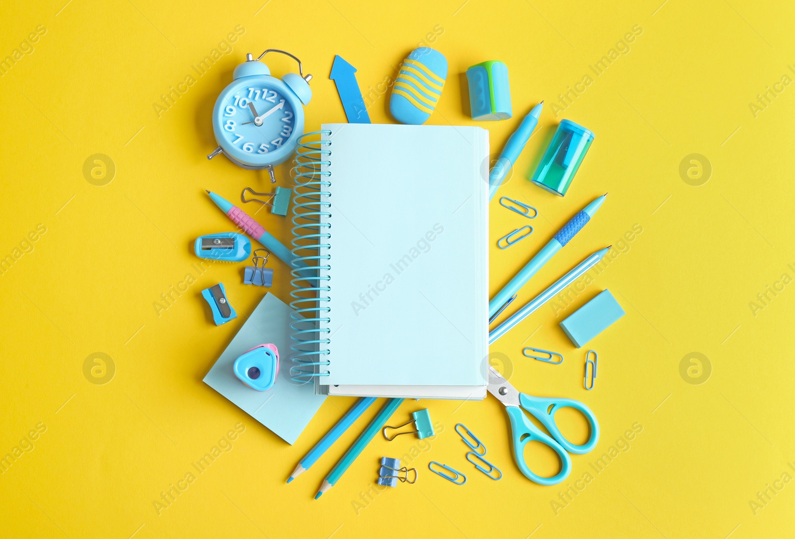 Photo of Different school stationery and blank notebook on yellow background, flat lay. Space for text